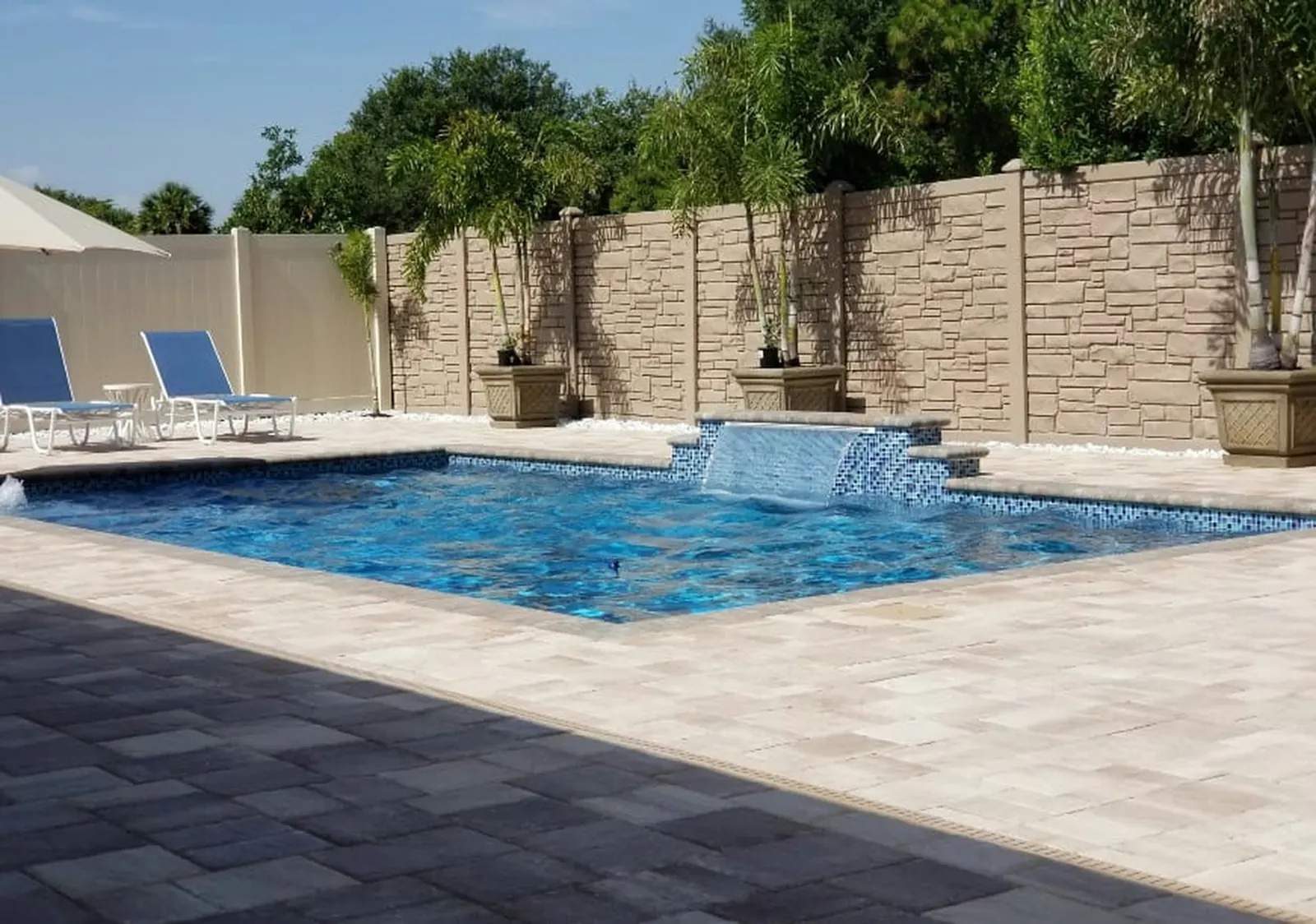 Sparkling clean backyard pool with a water feature and paver deck in San Marcos